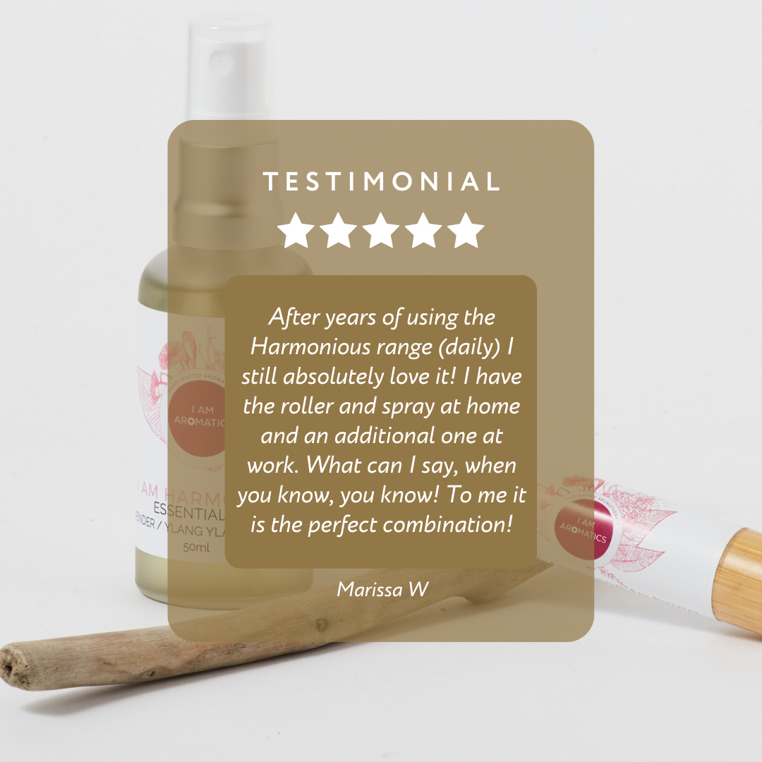 harmonious 50ml essential mist with matt silver atomiser, pink logo and font, pictured with a piece of driftwood and harmonious bamboo natural perfume roller 10mls