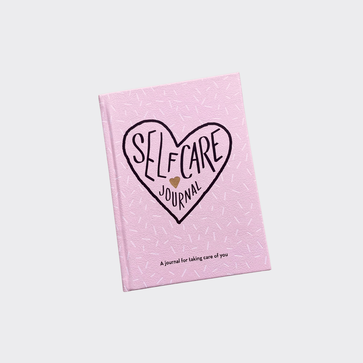 Self care journal / pink book with black writing inside a heart with a gold heart